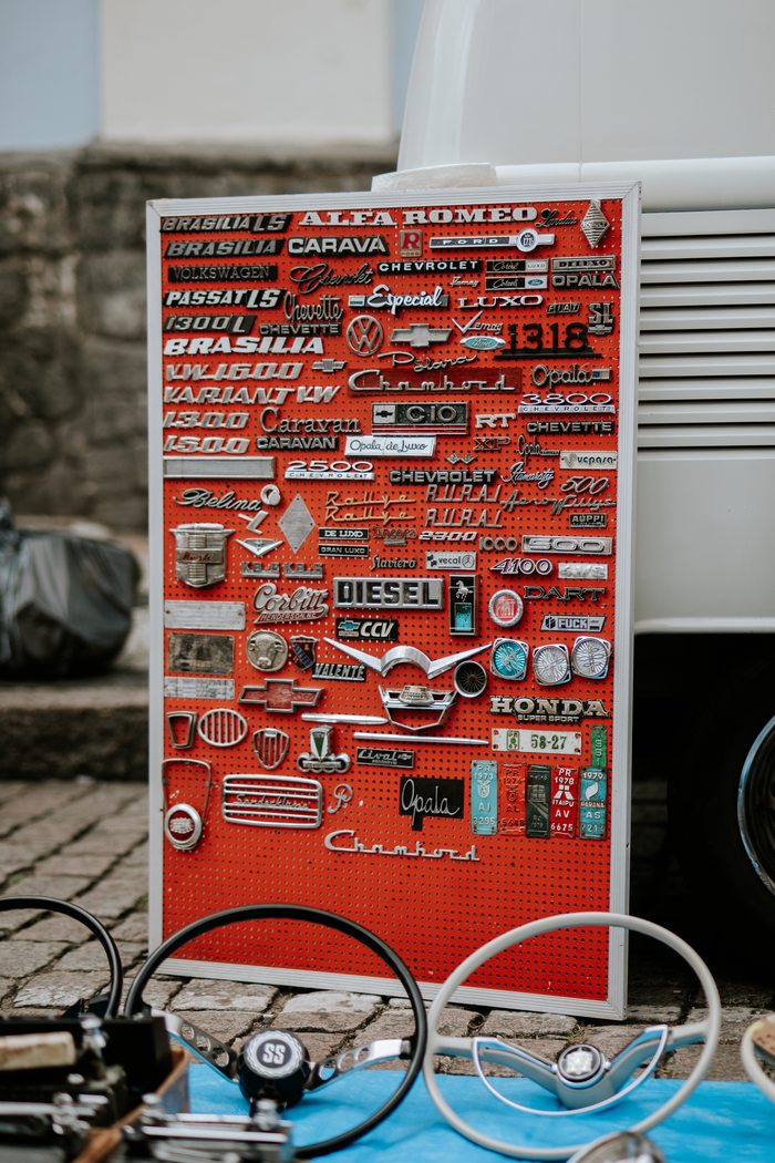 Collection of vintage car badges and parts on display at an outdoor flea market.